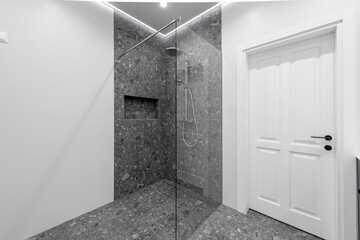 Modern White and Grey Tiled Home Bathroom Interior With Open Shower and Glass Partition.