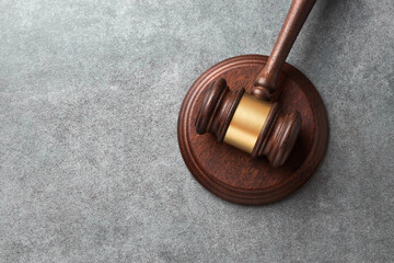 Judge's gavel on sound block on a gray stone surface. Represents courtroom authority and legal decisions. Top view with copy space.