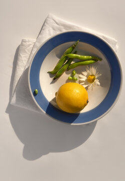 Fresh Lemon, Green Beans and Flower on white plate with a blue border.