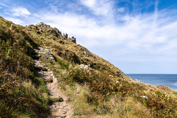 The South West Coast Path in Cornwall leading up a cliff, with a blue sky overhead