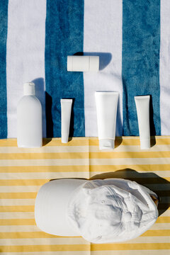 Flat lay of a cap and various skincare products arranged on towels