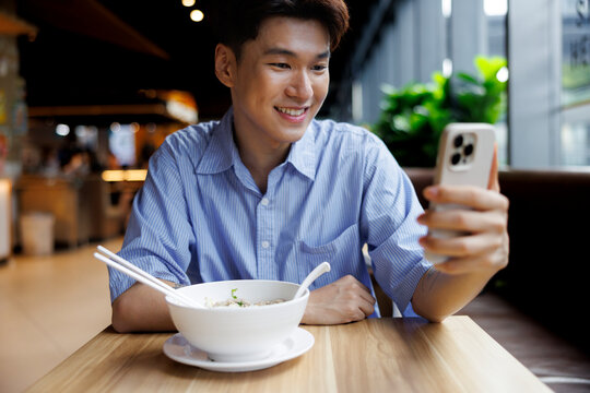 Smiling man video calls before eating noodles.