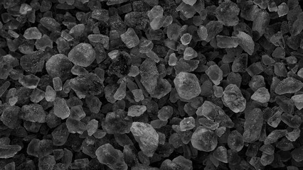 A pile of black rocks or crystals. They are wet, and their tiny grains serve as a textured...