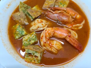 Thai sour curry, known as Gaeng Som (or Kaeng Som), served with shrimp, close-up overhead shot.