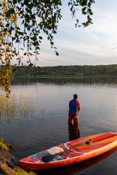 Man Fishing at Sunset with Paddleboard on Calm Lake