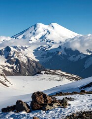 Majestic snow-capped mountain peak, surrounded by clouds and rocky terrain.  A panoramic vista of a high-altitude landscape