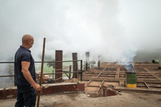 worker sweeping the top of a furnace in a charcoal factory