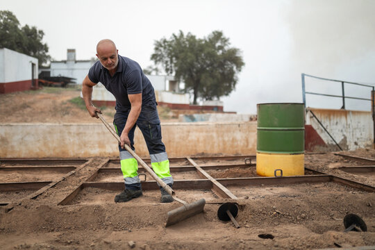 worker sweeping the top of a furnace in a charcoal factory