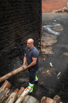Lumberjack arranging logs in charcoal factory