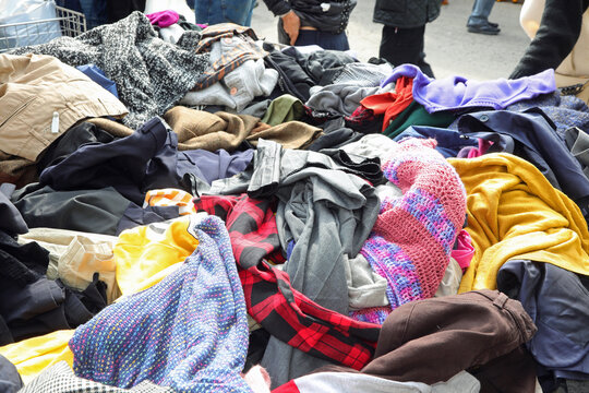 Disorganized stack of various pre owned fashion garments and outfits at an open air market