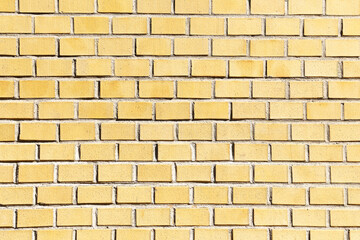 Naklejka premium Yellow brick wall background. Bright colorful texture of bricks with natural light and shadow. Construction material surface for architecture and design. Urban pattern and building element.