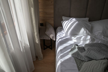 Sunlight falls on a bed in a bedroom.