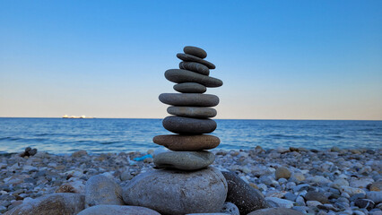 A tall cairn of perfectly balanced stones on a pebble beach, symbolizing zen, harmony, and serenity...