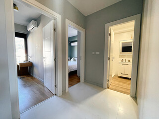 Contemporary Interior Hallway Featuring Multiple Doorways to Bedrooms and a Bright Kitchen Area in a Modern Apartment Design