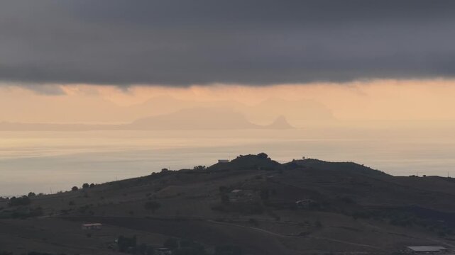 Aerial drone view of Capo Zafferano, a scenic Sicilian coastal promontory in the Metropolitan City of Palermo, Italy, featuring distant views of the Tyrrhenian Sea and the majestic Madonie Mountains