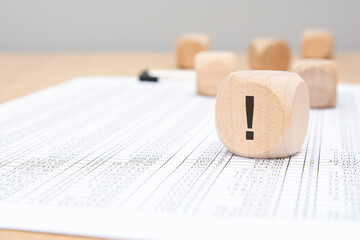 Wooden cube with exclamation mark on spreadsheet background