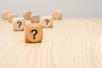 wooden cube with question mark in focus on wooden surface