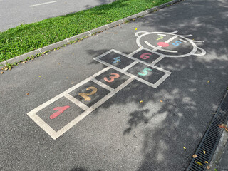 Hopscotch game painted on asphalt with numbers and a face