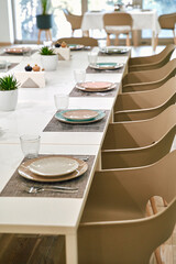 Modern Dining Space with Minimalist Decor Showcasing a Long Table Set for a Meal with Stylish Chairs and Elegant Tableware Surrounded by Natural Light