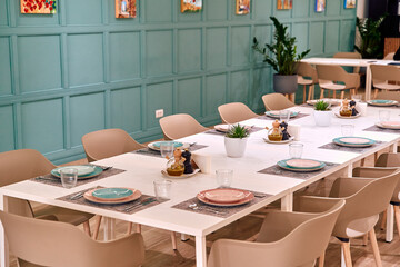 Modern Dining Room Setting with Elegant Table Arrangement Featuring Pastel Plates, Glassware, and Minimalist Decor in a Stylish Green Space