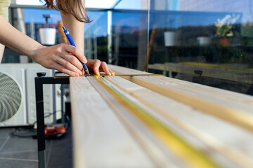 Professional carpenter woman hands working with a ruler and making marks on the wood at in the home balcony.