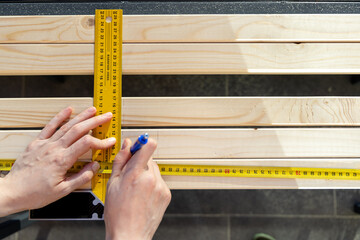 Professional male worker apply tape measure on wooden plank for further cutting