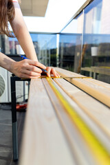 Professional carpenter woman hands working with a ruler and making marks on the wood at in the home balcony.