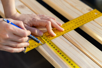 Professional male worker apply tape measure on wooden plank for further cutting