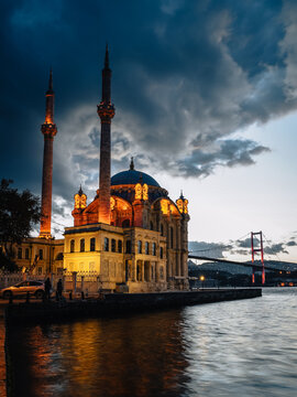 View of the illuminated Ortak&Atilde;&para;y Mosque stands majestically on the waterfront, its reflection shimmering on the water under a dramatic sky, Istanbul, &Auml;&deg;stanbul, T&Atilde;&frac14;rkiye.