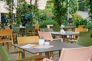 Charming Outdoor Dining Area Featuring Colorful Chairs and Tables Surrounded by Lush Greenery and Decorative Elements for a Cozy Ambiance
