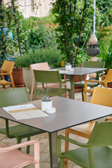 Charming Outdoor Dining Area Surrounded by Lush Greenery Featuring Colorful Chairs and Modern Tables for Relaxing Meals and Social Gatherings
