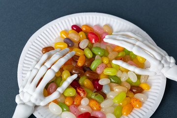Skeleton hands holding plate of colorful jelly beans