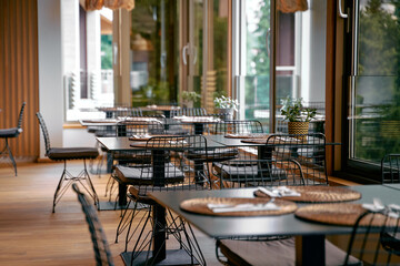 Modern Restaurant Interior Featuring Stylish Tables and Elegant Decor in a Bright, Open Space with Natural Light Streaming Through Large Windows