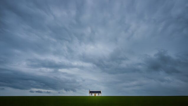 Lone figure stands on a vast green field under a dramatic cloudy sky