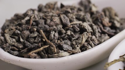 Green dried gunpowder chinese tea leaves with scoop on white wooden background, closeup. - Powered by Adobe