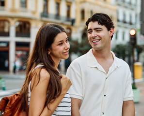 Fototapeta premium Portrait of a smiling couple in the city, tourists visiting destination, summer trip exploring, beautiful couple having fun outdoors