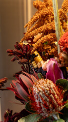 Autumn atmospheric flower arrangement in warm tones. Close-up. Red banksia, leucadendron, lily,...