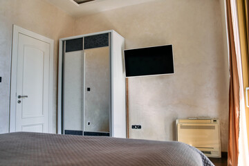 Stylish and Cozy Bedroom Interior Featuring Modern Furniture, Wall-mounted TV, and Elegant Décor in Subtle Earthy Tones