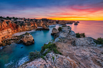 Sunset over Algarve cliffs with golden light reflecting on the ocean, capturing the rugged beauty of the coastline.