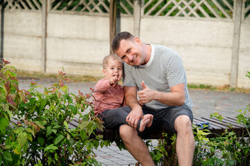 Father enjoys quality time with young son while sitting in a garden during a sunny afternoon