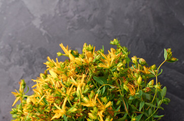Vibrant yellow thyme flowers with lush green leaves are arranged beautifully against a textured dark background, showcasing the natural beauty and elegance of floral design