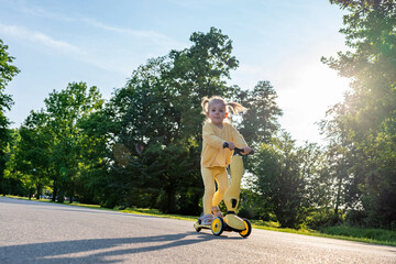 Child scooter riding. Girl yellow scooter park. Motion day lifestyle travel.