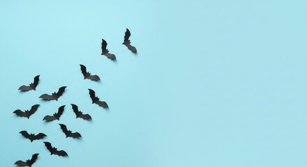 Fototapeta premium Flying black paper bats on pastel blue background, minimal Halloween style