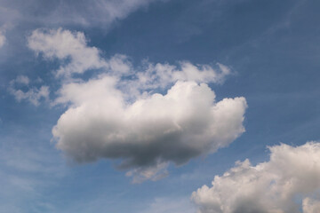 A Single Large White Cumulus Cloud Floating In A Blue Sky With Wispy Clouds Around It. Natural Weather Background With Copy Space.
