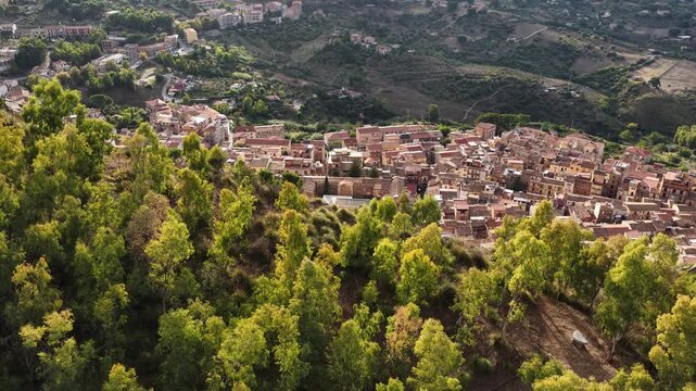 Aerial drone view of Collesano Sicilian mountain town at sunset with Basilica San Pietro church and historic stone streets in the Madonie Mountains, Sicily, Italy. Old mountain town in Sicily