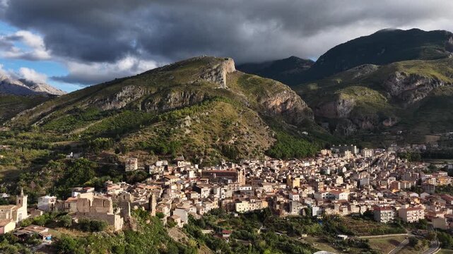Aerial drone view of Collesano Sicilian mountain town at sunset with Basilica San Pietro church and historic stone streets in the Madonie Mountains, Sicily, Italy. Old mountain town in Sicily