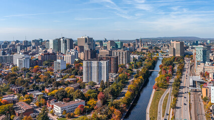 Stunning aerial view of downtown Ottawa, Ontario, Canada, with the Rideau Canal lined with vibrant autumn foliage, Gatineau Hills behind, capturing the beauty of fall in the capital (October 2025) © J Duquette