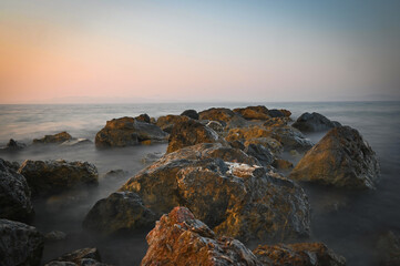 Rocky Seashore at Sunset with Soft Waves and Long Exposure Effect