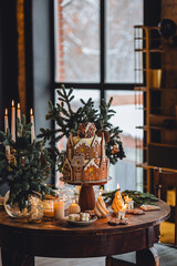 Family holiday celebration. Beautiful traditional homemade gingerbread house. Celebration of Christmas and Happy new year at home. Festive mood, cozy atmosphere, burning candles, fir tree branches