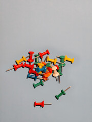Colorful plastic push pins scattered on light blue background